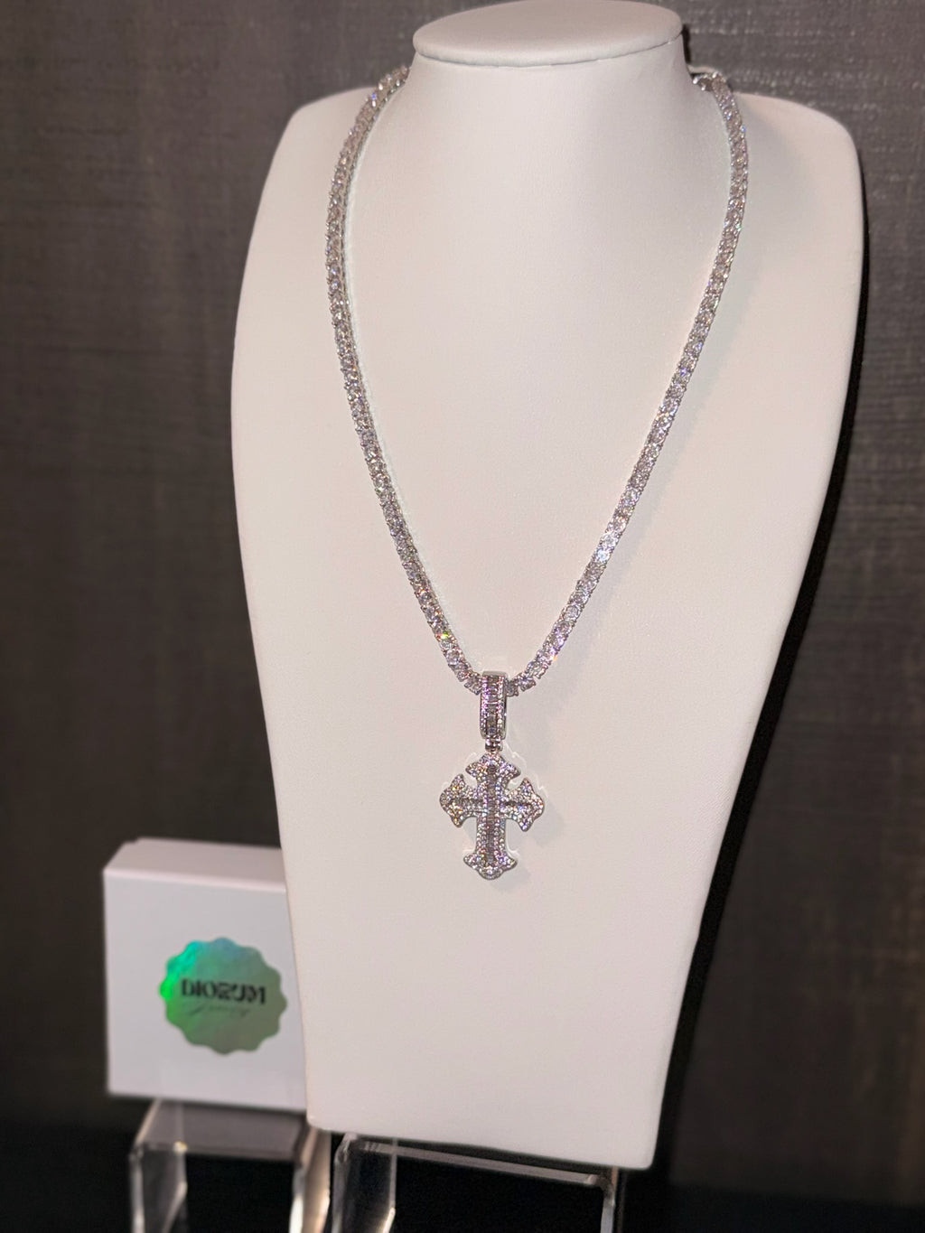 White gold plated tennis chain and iced cross pendant.