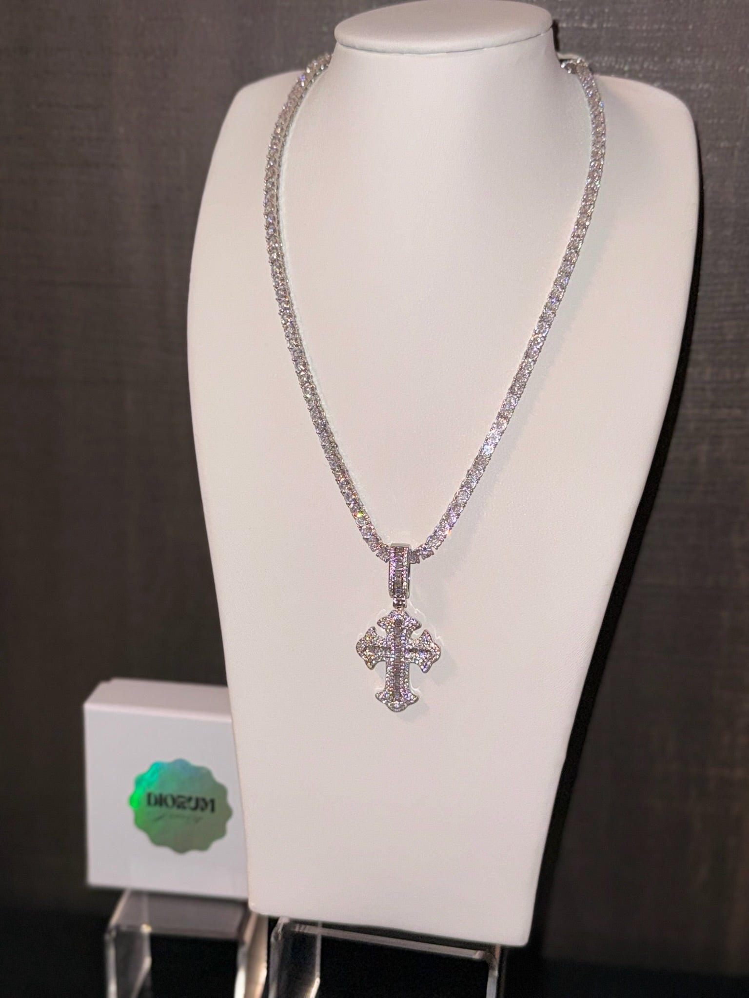 White gold plated tennis chain and iced cross pendant.