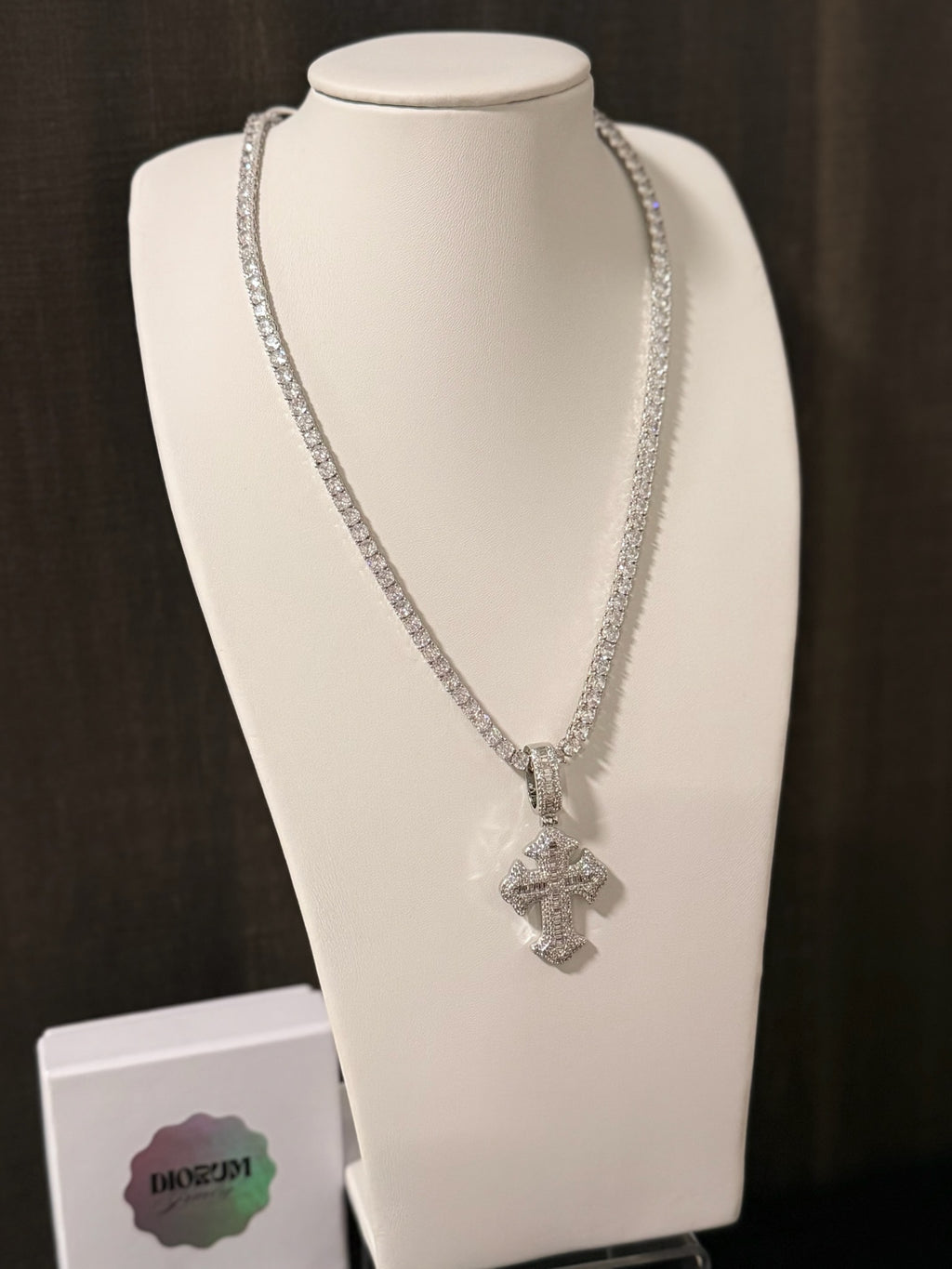 White gold plated tennis chain and iced cross pendant.